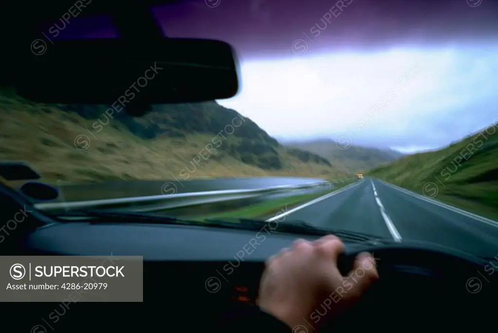 View from drivers seat of man driving car on wet road in NOrthern Ireland, with blurred effect.