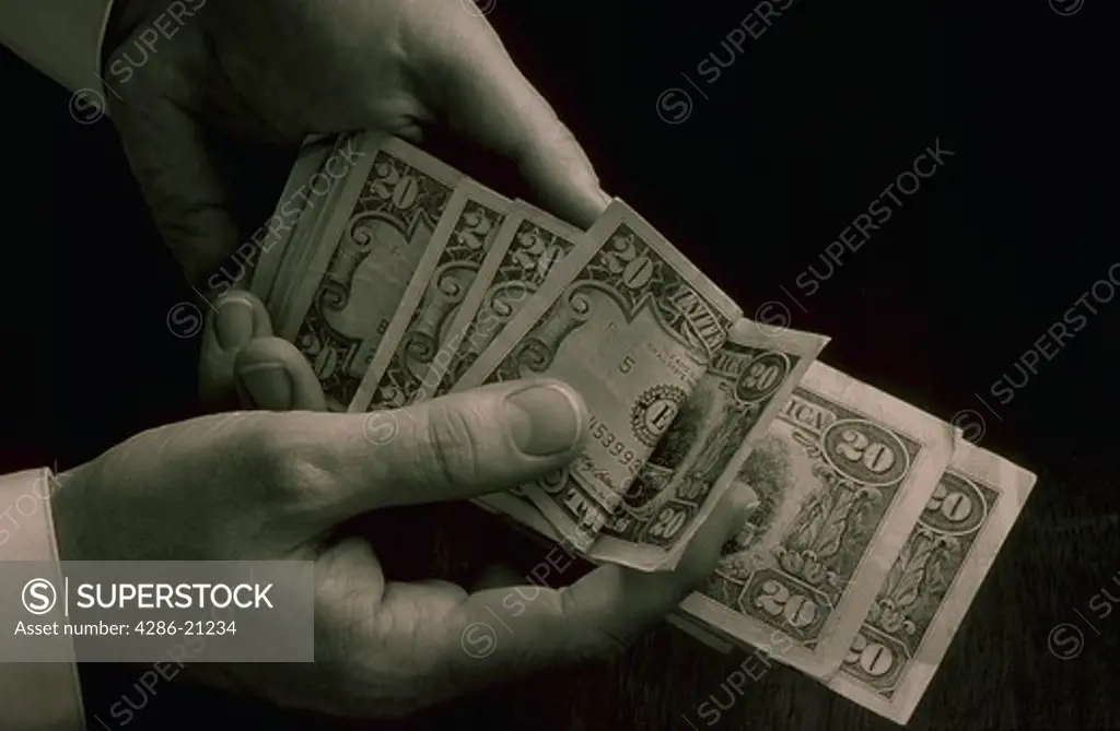 Hands flipping through twenty dollar bills