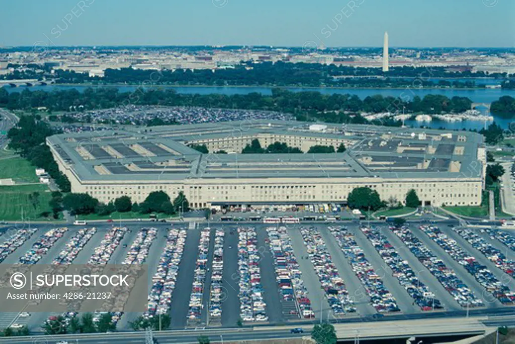 Oblique aerial view of the Pentagon and its vast parking lots. Washington DC lies beyond behind the Potomac River.