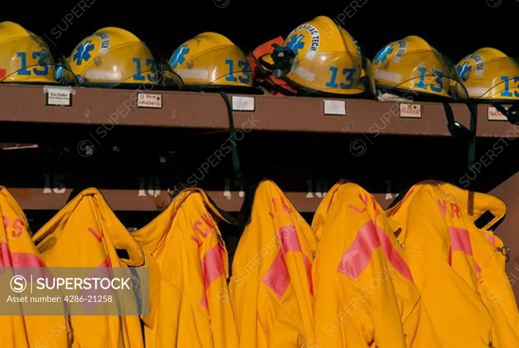 Bright yellow firefighters turnout gear (coats and helmets) stored on a ready rack organized for instant use.