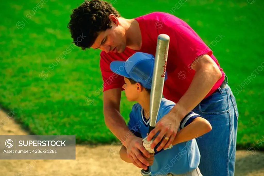 Dad/coach helps youth league player work on batting abilities.MR