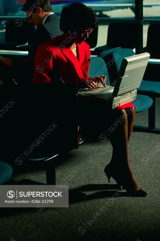 Female executive works with laptop computer while waiting at airport.Harrisburg International Airport,PA.MR