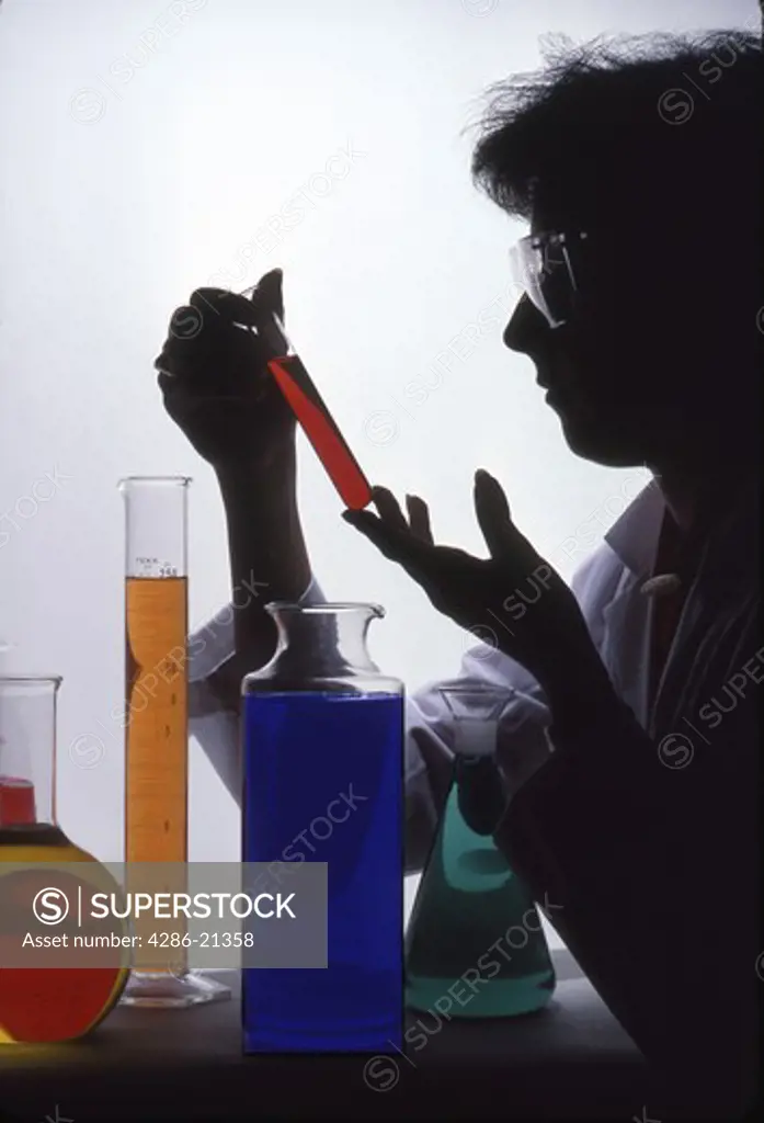 Chemist examines liquid in cylinder 