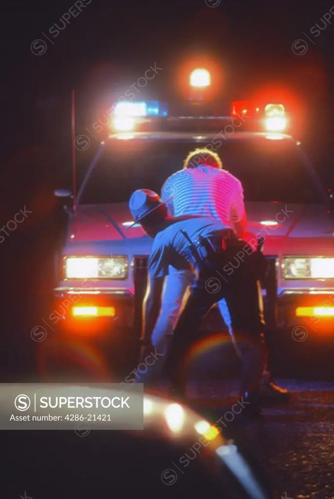 Policeman frisks teen male at car