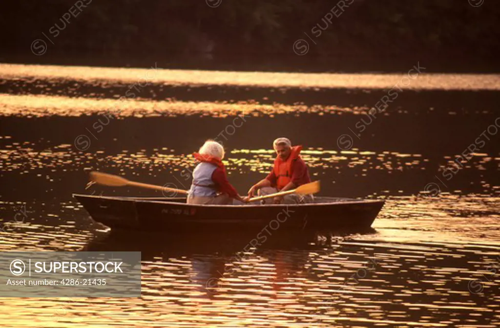 Senior couple. rowboat, sunset 