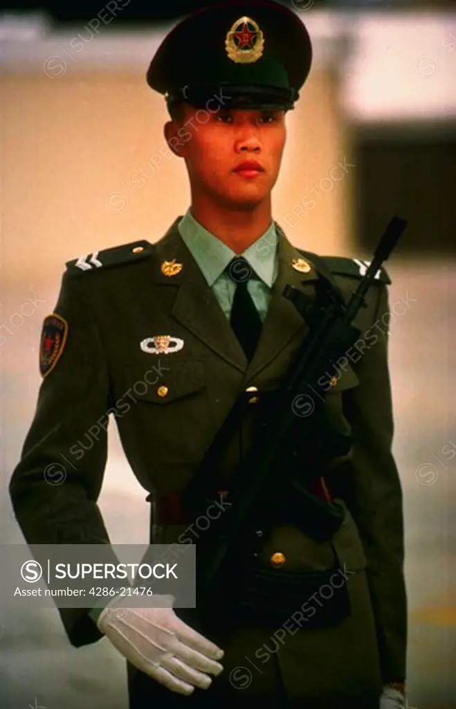 PLA soldier standing at attention while holding semi-automatic weapon.