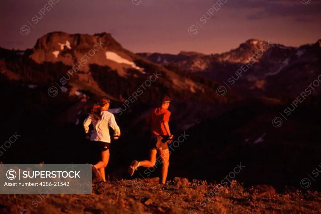 A man and woman running at sunset on Mount Lincoln, CA.