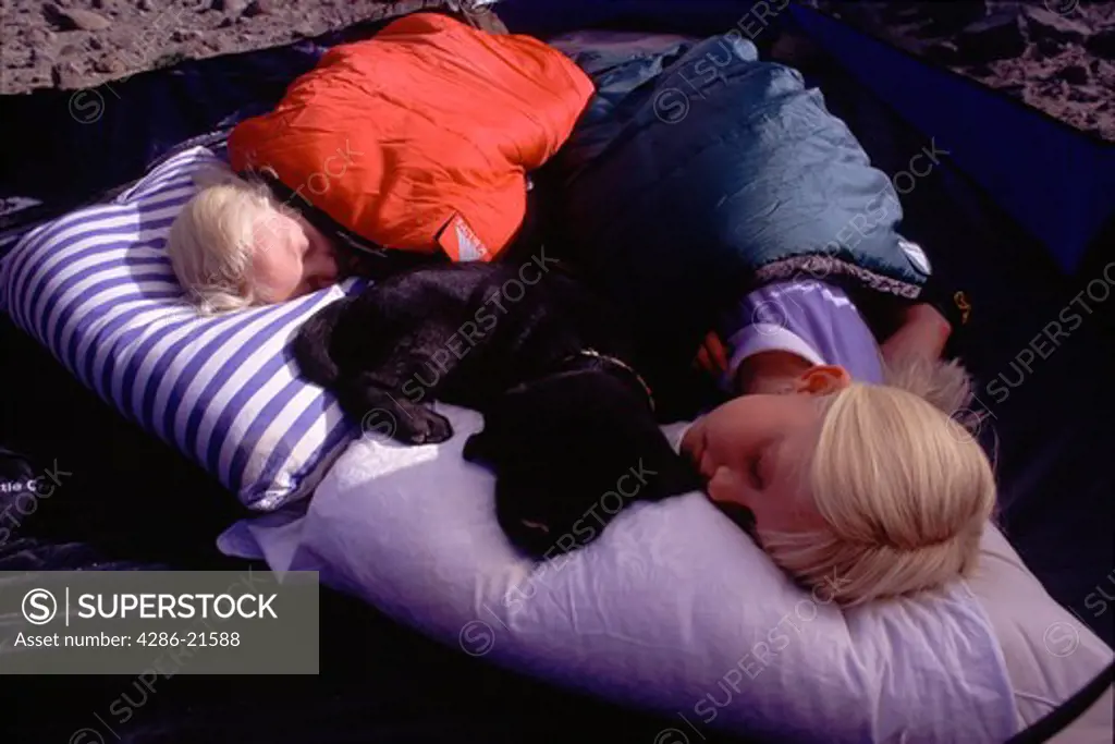 Two young sisters taking a nap while camping on Mount Judah, CA.