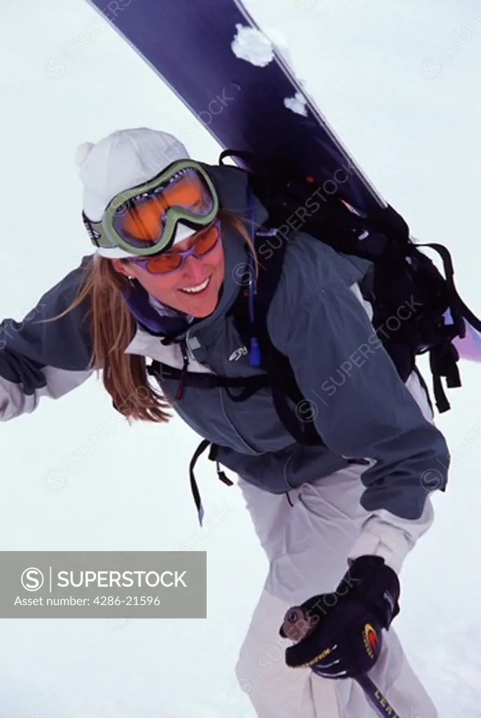 A woman hiking Mount Millicent while snowboarding near Brighton, UT.