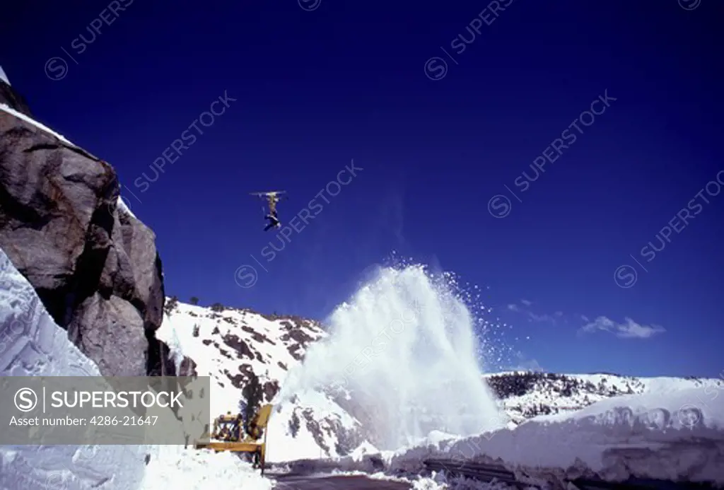 A woman jumping over a road while skiing on Donner Summit, CA.