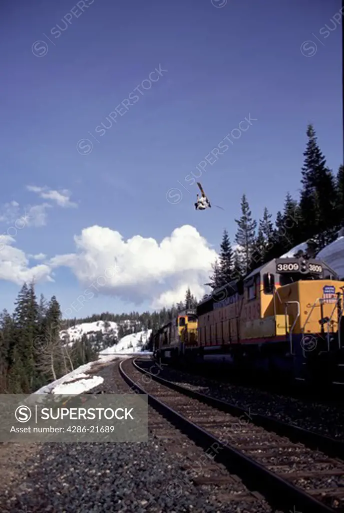 A man jumping over a train while skiing in Cisco Grove, CA.