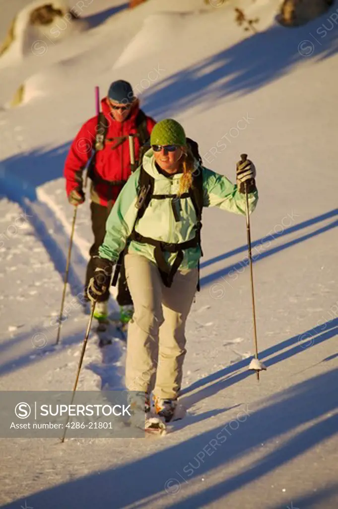 A couple hiking uphill on skis.