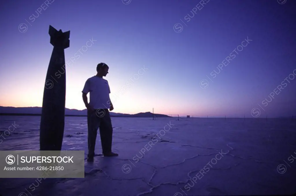 A man standing next to a fake bomb on the Bonneville Salt Flats in Utah.