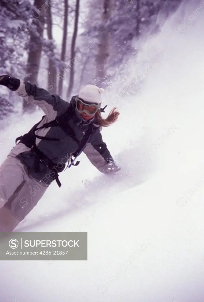 A woman snowboarding in a snow storm on Mount Millicent near Brighton, UT.