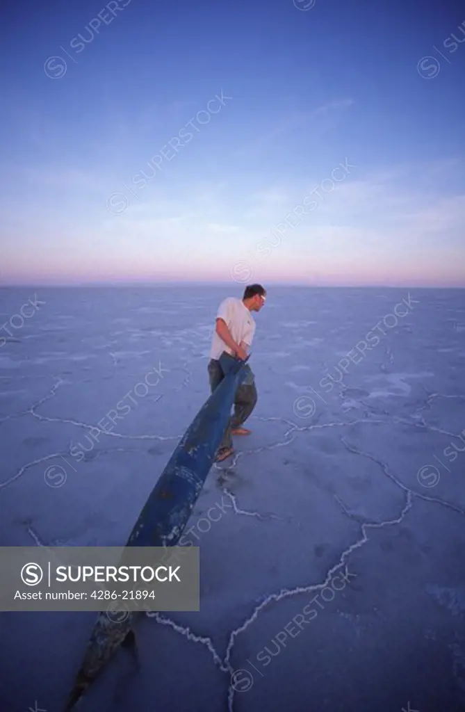 A man pretendsing to steal a fake bomb on the Bonneville Salt Flats in Utah.