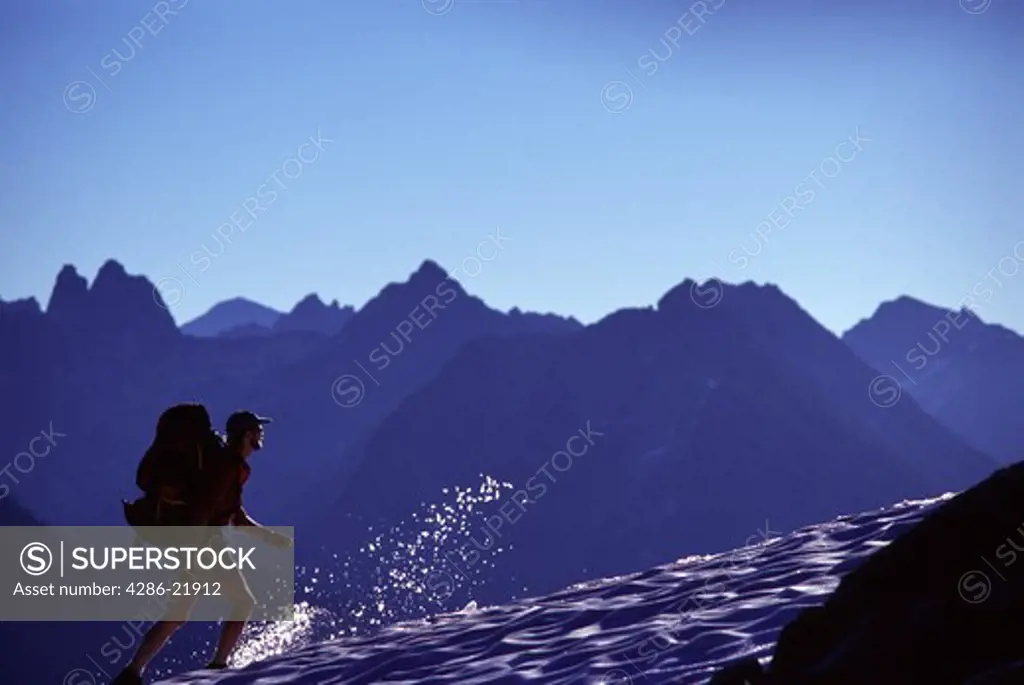 A man hiking on snow during the summer near Maple Pass, WA.