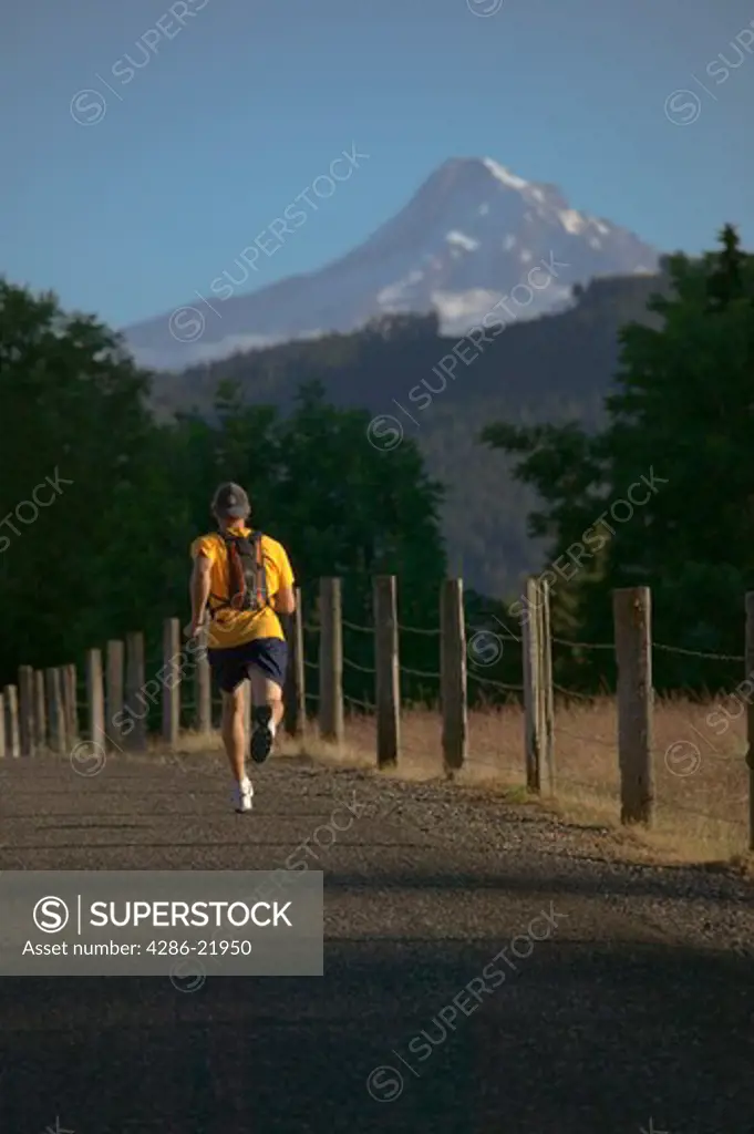 A man running on a road with Mount Hood in the background.