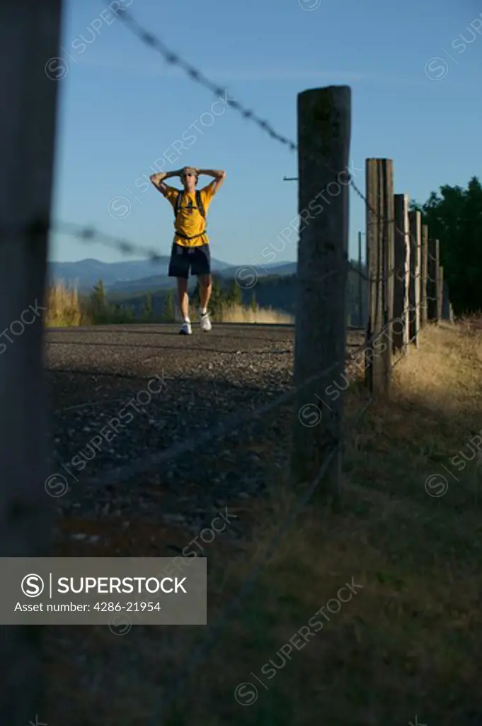 A tired runner walking a road alongside a fence in White Salmon, WA.