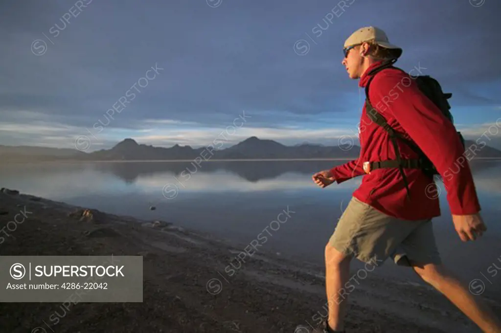 A man hiking on the Bonneville Salt Flats in Utah while listening to an MP3 player.