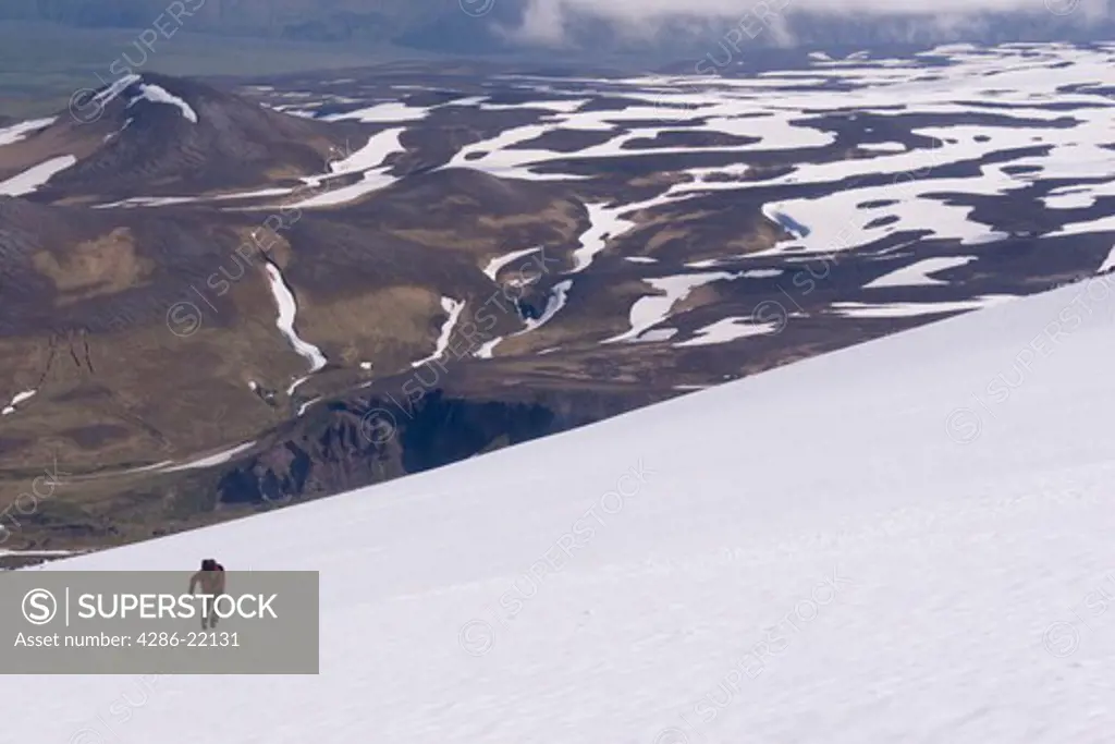 A skier climbing Mount Vsevidov in the Aleutian islands Alaska with the tundra below.