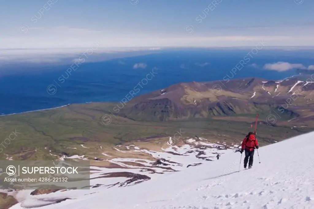 Two skiers climbing Mount Vsevidov in the Aleutian islands with the Bering Sea below.
