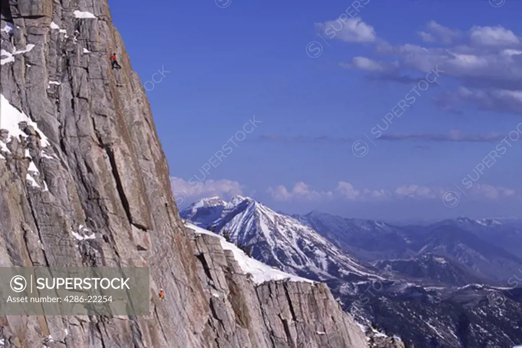 A couple rock climbing the Triple Overhangs route on Lone Peak, UT.