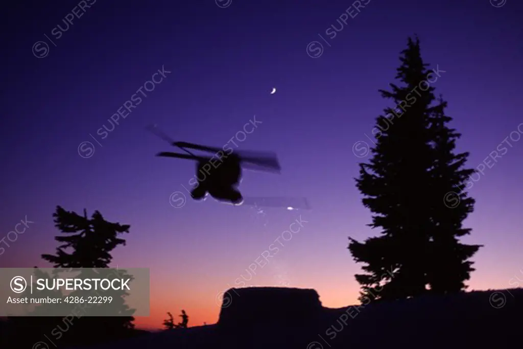A man jumping while skiing at Mount Hood, OR. after sunset.