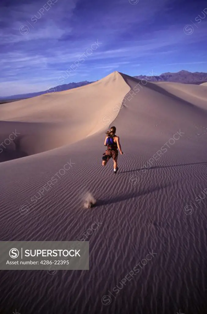 A woman running up a sand dune in Death Valey, CA.