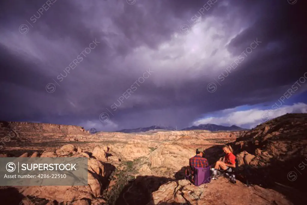 Two People Camping Beneath Storm Clouds Near Moab, Utah