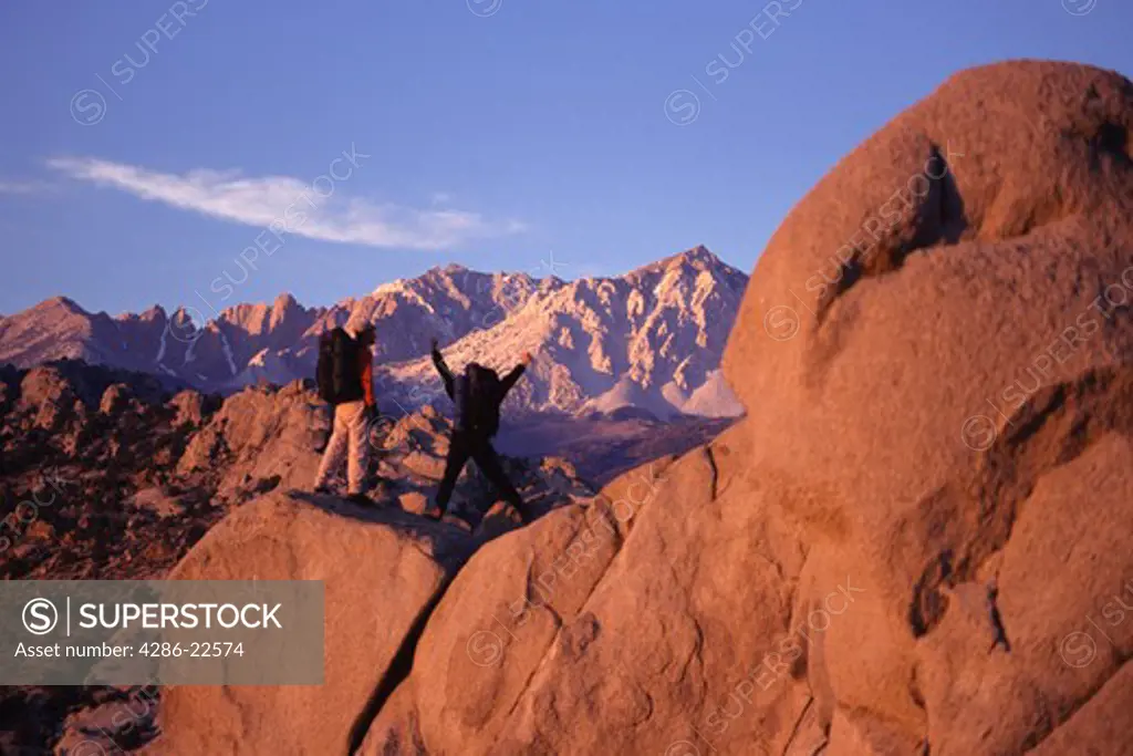 A couple hiking at dawn in the Buttermilk boulders in the California Sierra mountains.