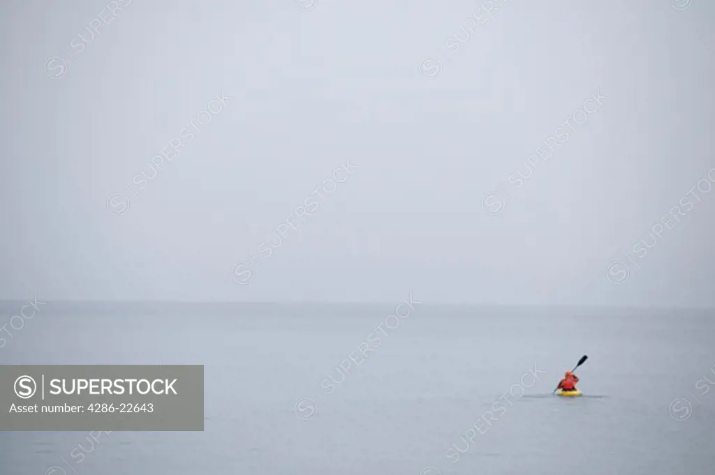 A man kayaking on Lake Tahoe in the fog in winter.