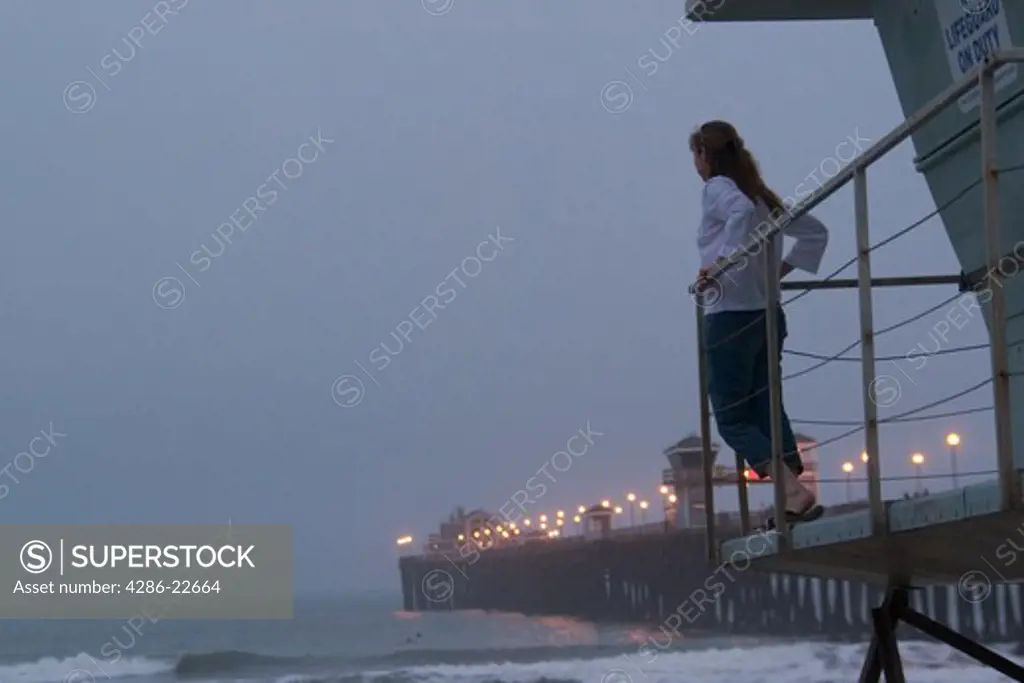A woman looking at the Oceanside pier at dusk.