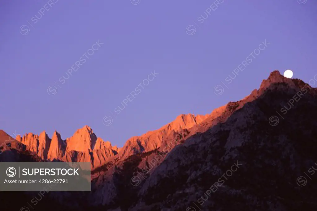 Mount Whitney and moon at sunrise in the Sierra mountains in California at sunset.