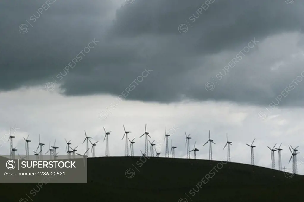 A silhoutte of windmills on a hillside on a cloudy day near Livermore, California