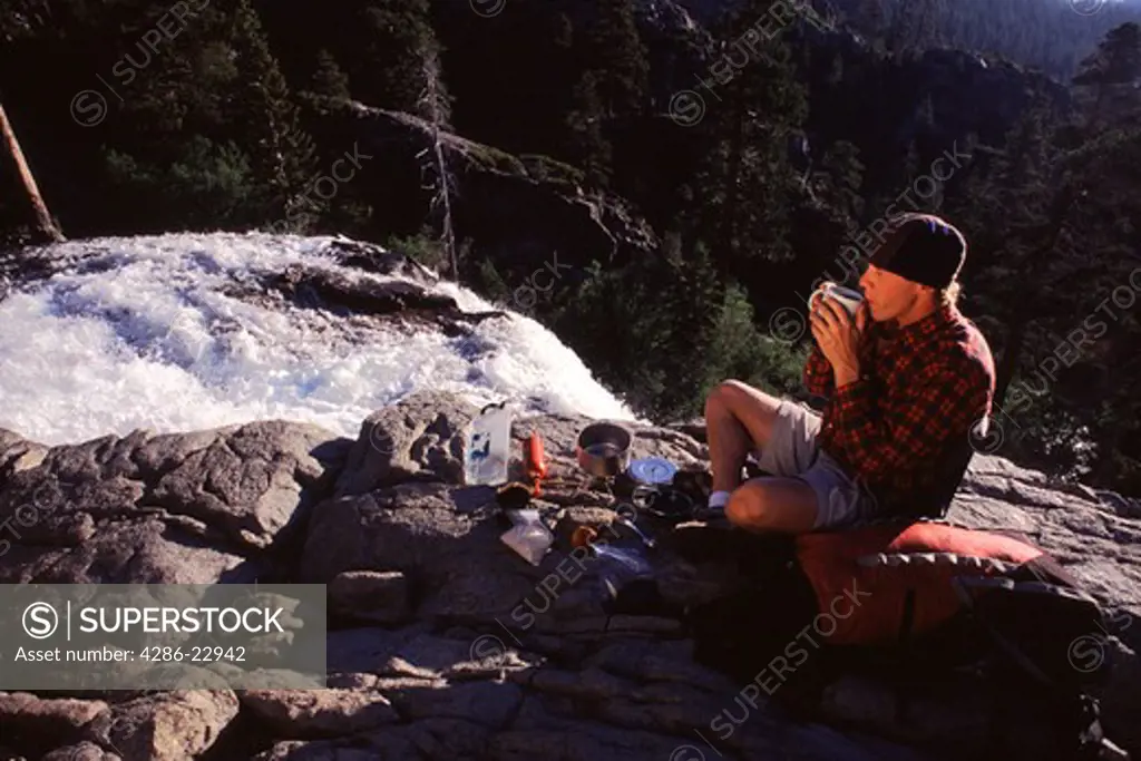 A man drinking tea by a waterfall near Lake Tahoe in California.