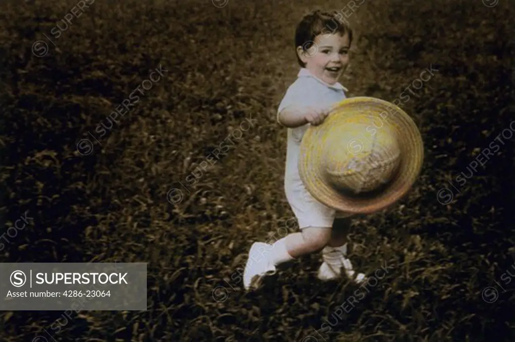   Hand colored image of 5yo boy running  in white shorts, shoes, and straw hat.