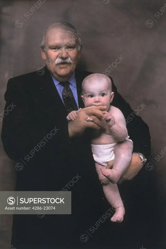   Hand colored portrait of grandfather and grandchild or elderly businessman holding baby who is biting his hand .
