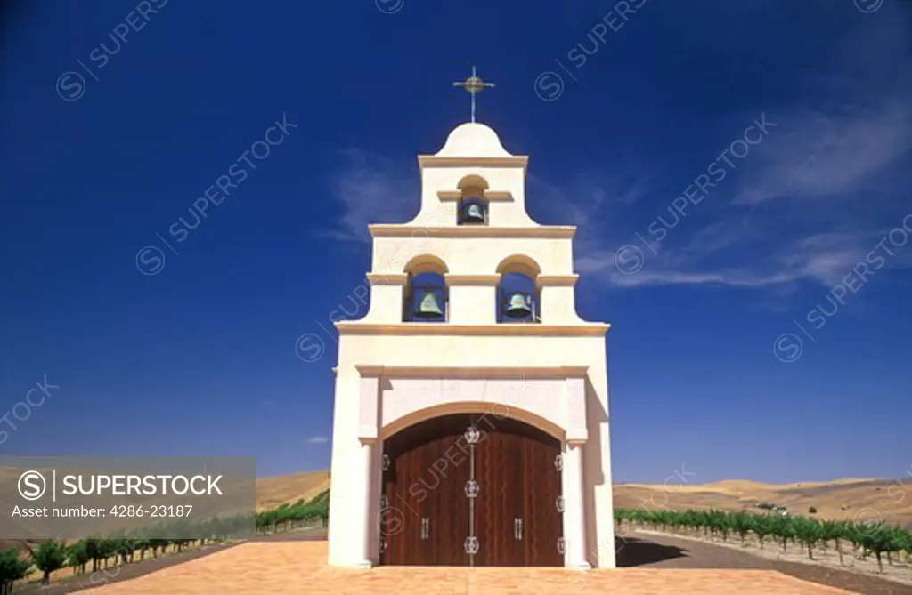 USA, California, Paso Robles, Spanish Mission style church on hill with grape vineyard