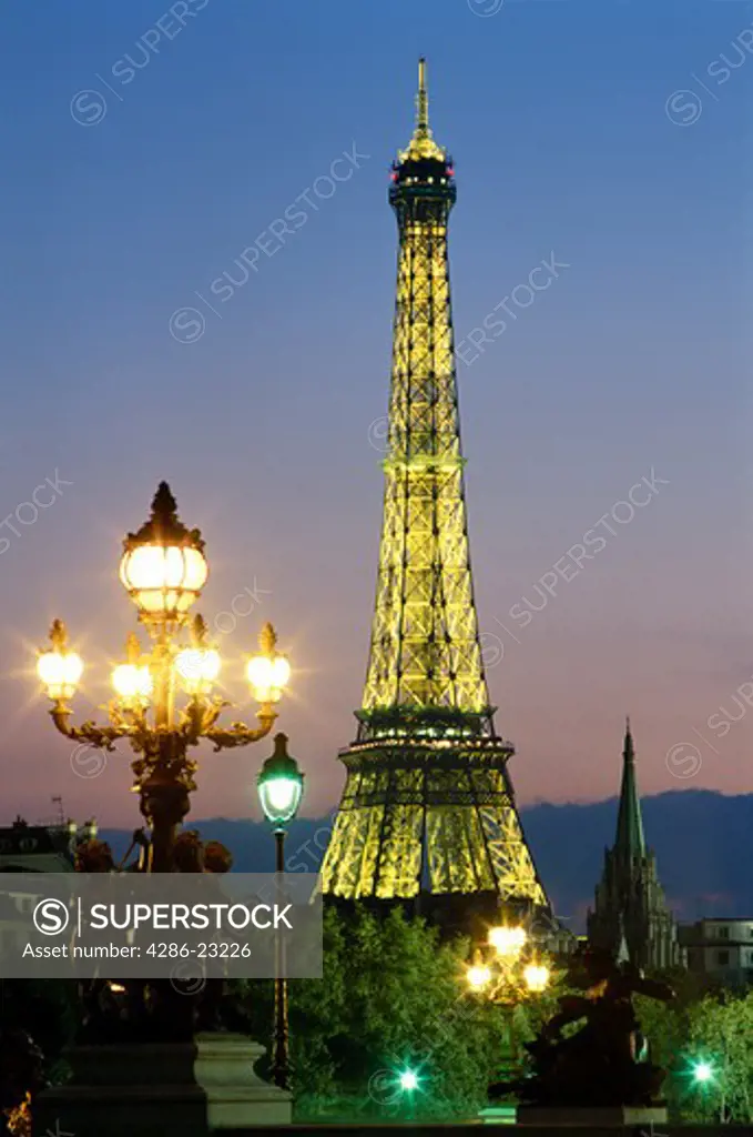 France Paris Eiffel Tower illuminated at dusk and lamp post