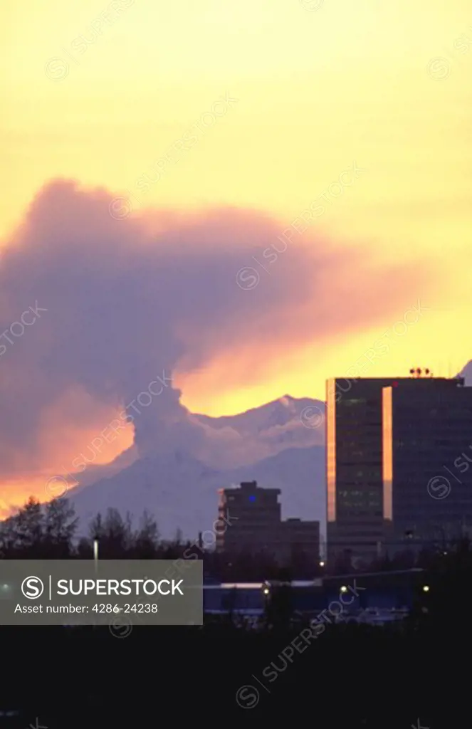 Mt. Spur Volcano, at sunset, spewing steam and ash  over the Anchorage city skyline, Anchorage, Alaska.