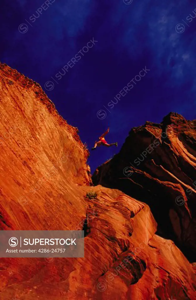 Man leaping across rock formations, Sterling Canyon, Arizona.