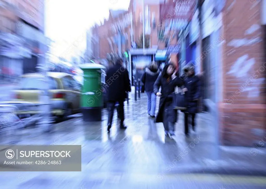 People walking on rainy city street, pan blur
