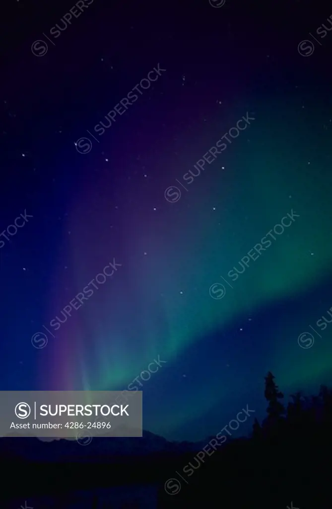 A blue and green Aurora Borealis at dusk with the Big Dipper  and Mount McKinley at Trapper Creek, Alaska.