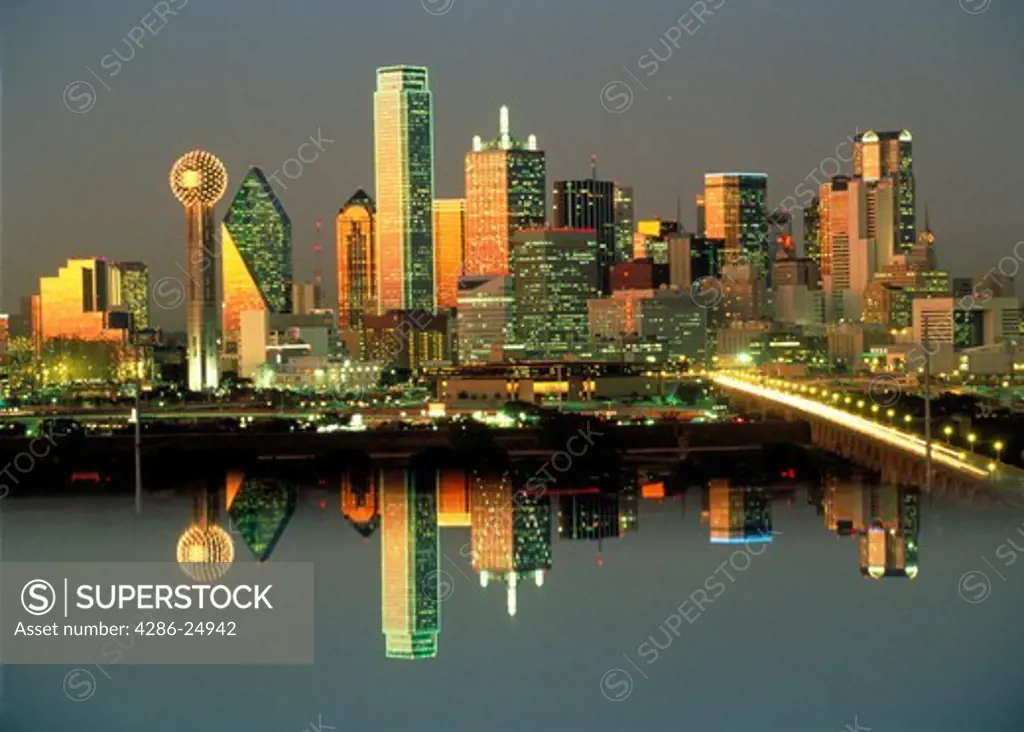 Dallas skyline at dusk, with reflections on water.