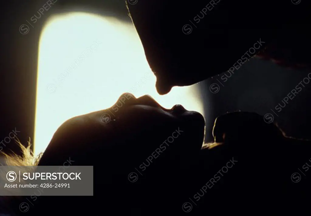 Silhouette of a newborn baby feeding from the mothers breast.