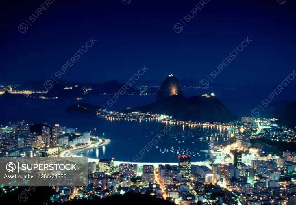 Aerial view of Rio de Janeiro with city lights at night, Brazil.  Sugar Loaf (Pao de Acucar) and Botafogo are visible.