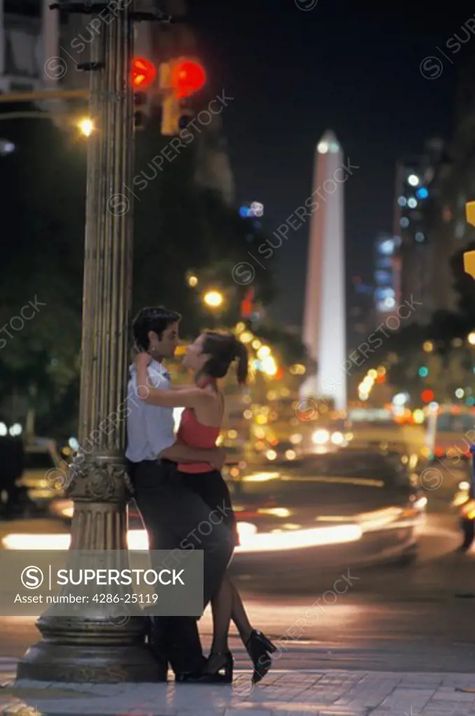 Couple at Plaza De Mayo with Obelisk beyond at night in Buenos Aires