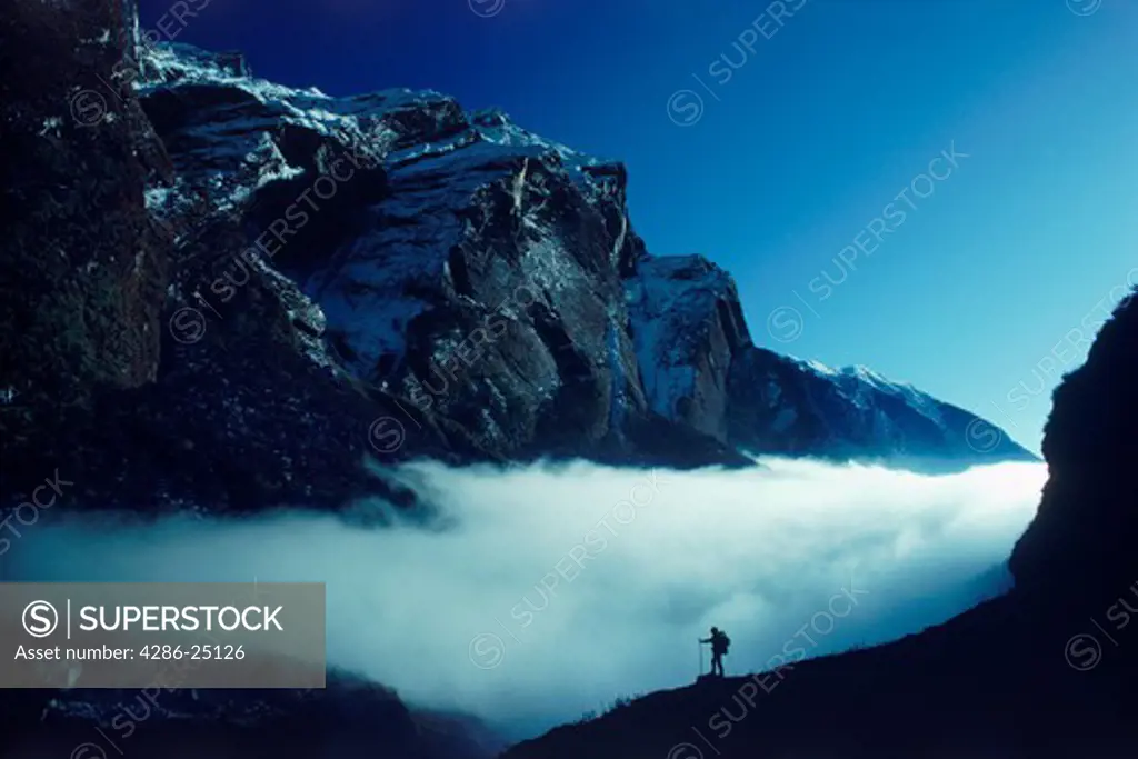 Hiker in Himalayas beneath Machipucharre and above the clouds