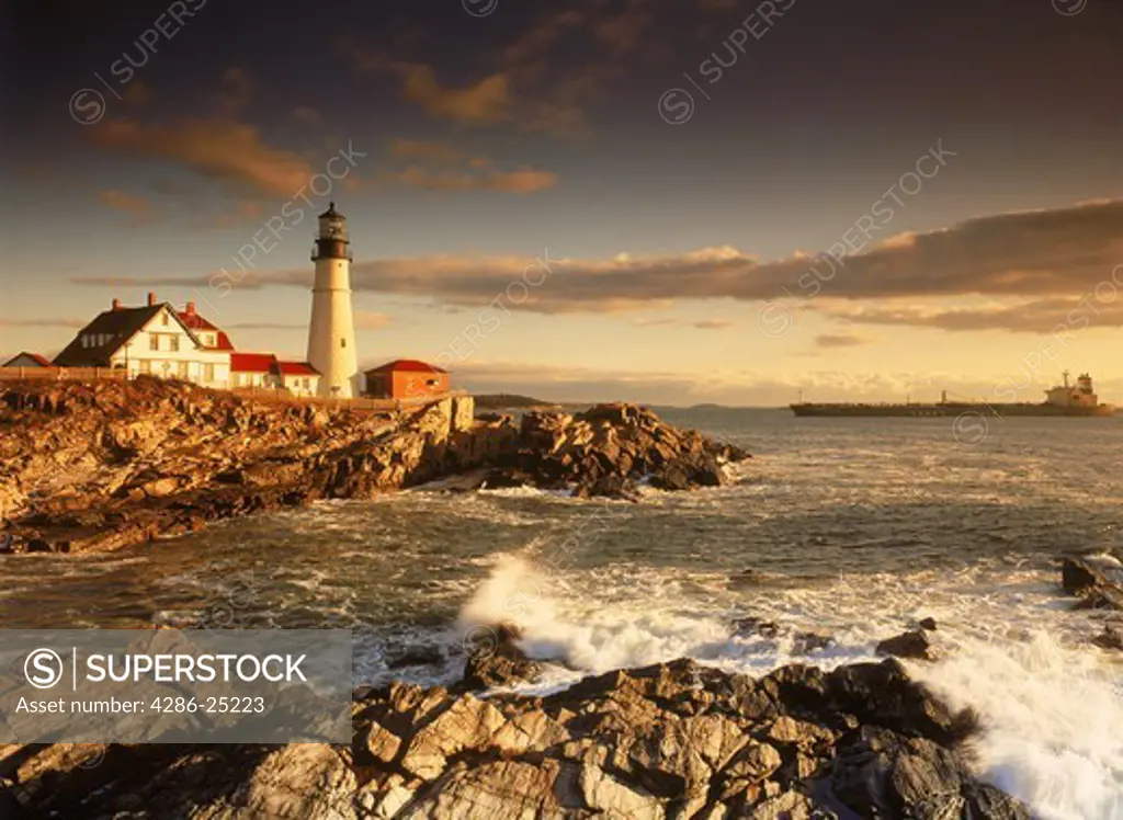 Ship passing Portland Head Lighthouse on coast of Maine at sunrise