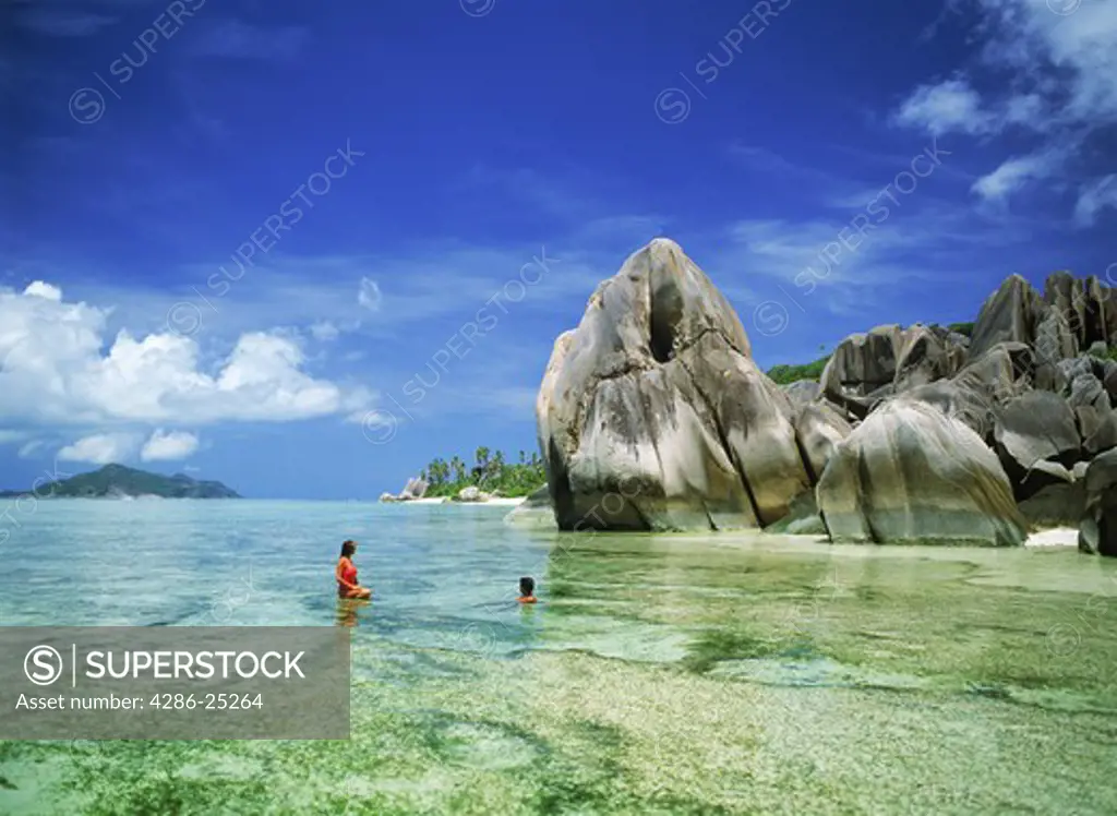 Couple in aqua waters along Anse Source d Argent on La Digue in Seychelles 